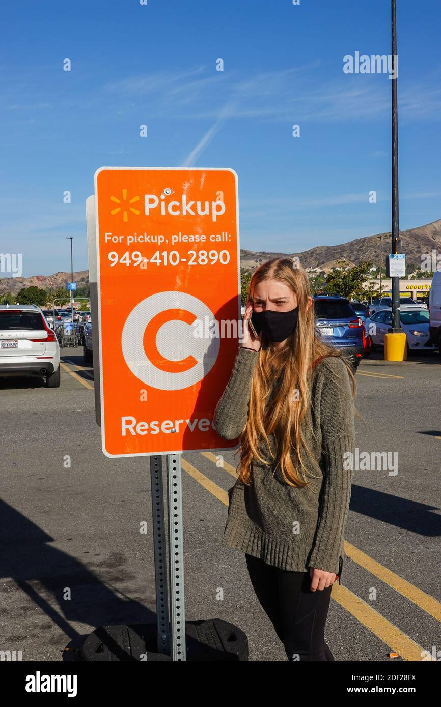 Giovane donna che chiede il ritiro in riva al marciapiede in un parcheggio Walmart a Foothill Ranch, California, USA Foto Stock