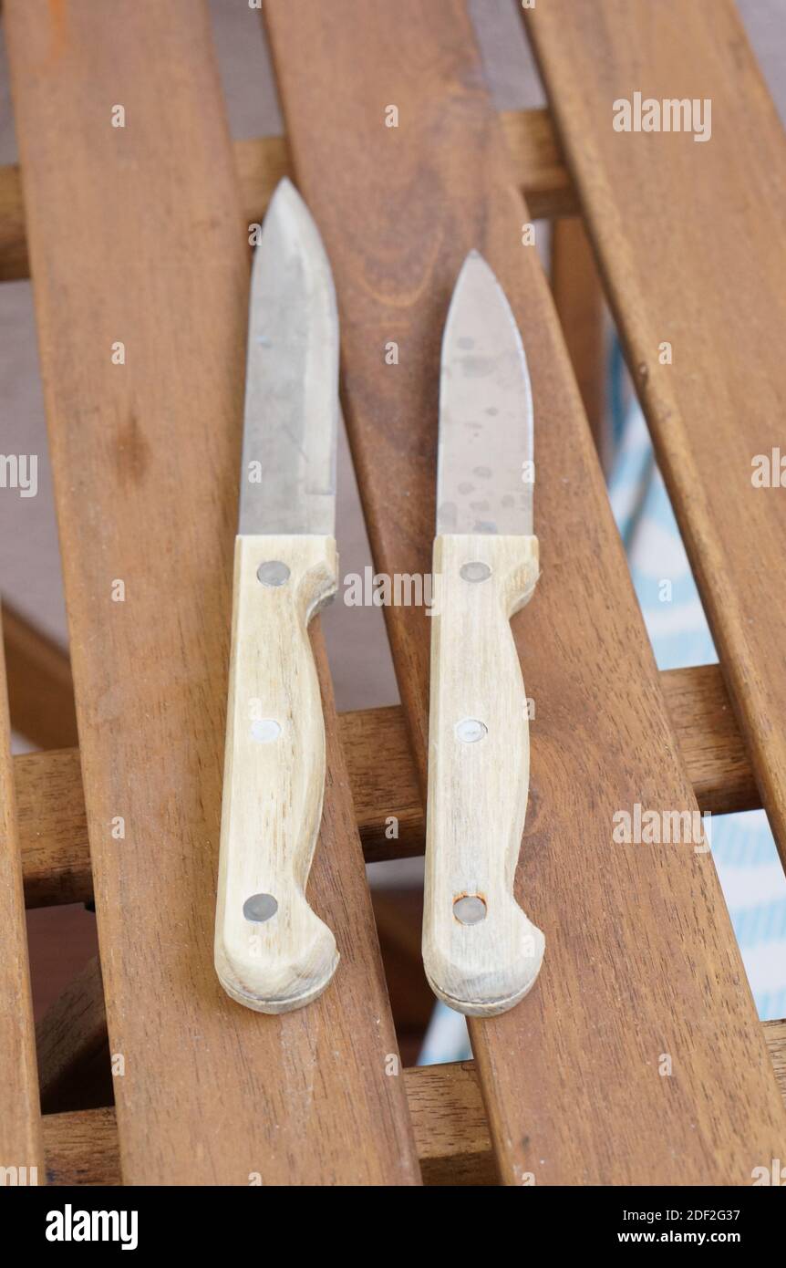 Due coltelli bianchi affilati posati su un tavolo di legno Foto Stock