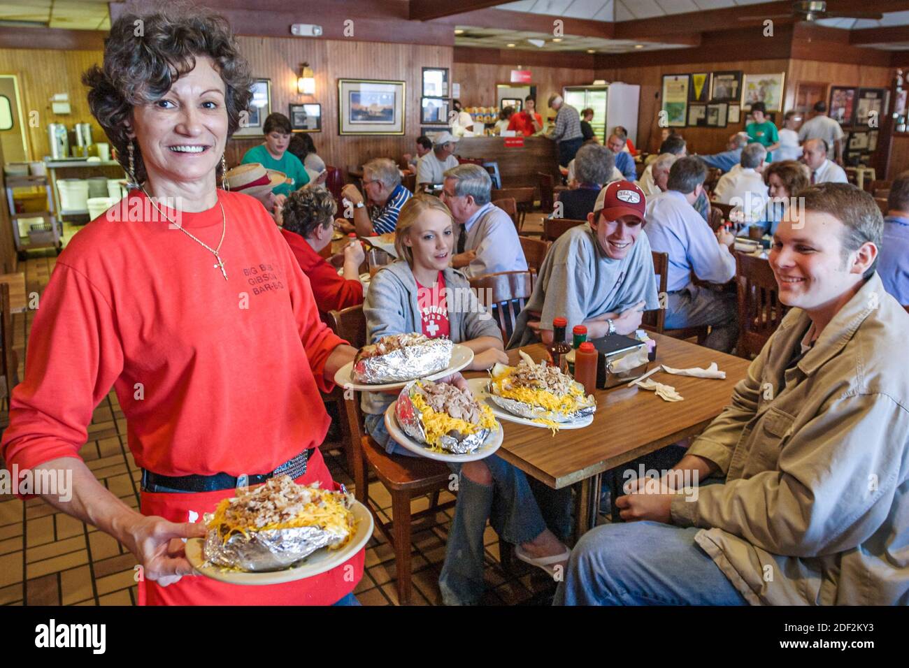 Alabama Decatur Big Bob Gibson BBQ ristorante, interno donna cameriera server donna donna cameriera che serve pollo di manzo di maiale, bar-b-q farcito patate al forno, Foto Stock
