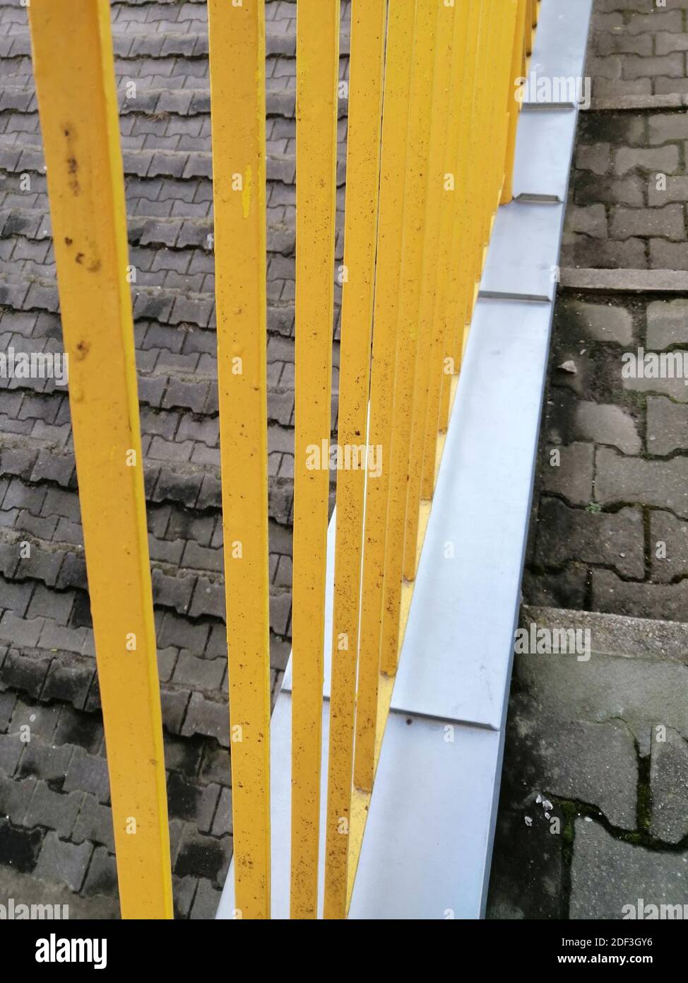 Colpo verticale di una recinzione metallica gialla attaccata alle scale Foto Stock