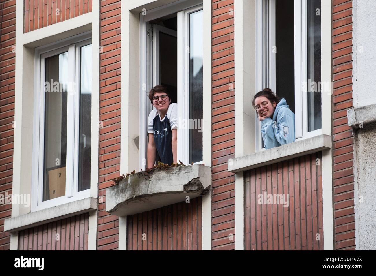 Le donne sorridono alla loro finestra il 21 marzo 2020 a Lille, durante COVID-19 come un blocco rigoroso entra in vigore per fermare la diffusione della malattia di Coronavirus. Foto di Julie Sebadelha/ABACAPRESS.COM Foto Stock