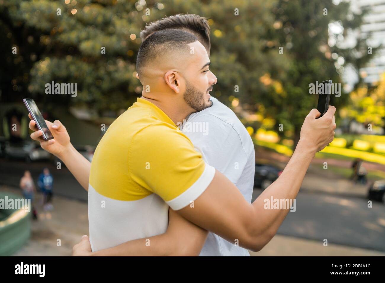Una coppia gay si agganava mentre ognuno usa il proprio telefono. Foto Stock