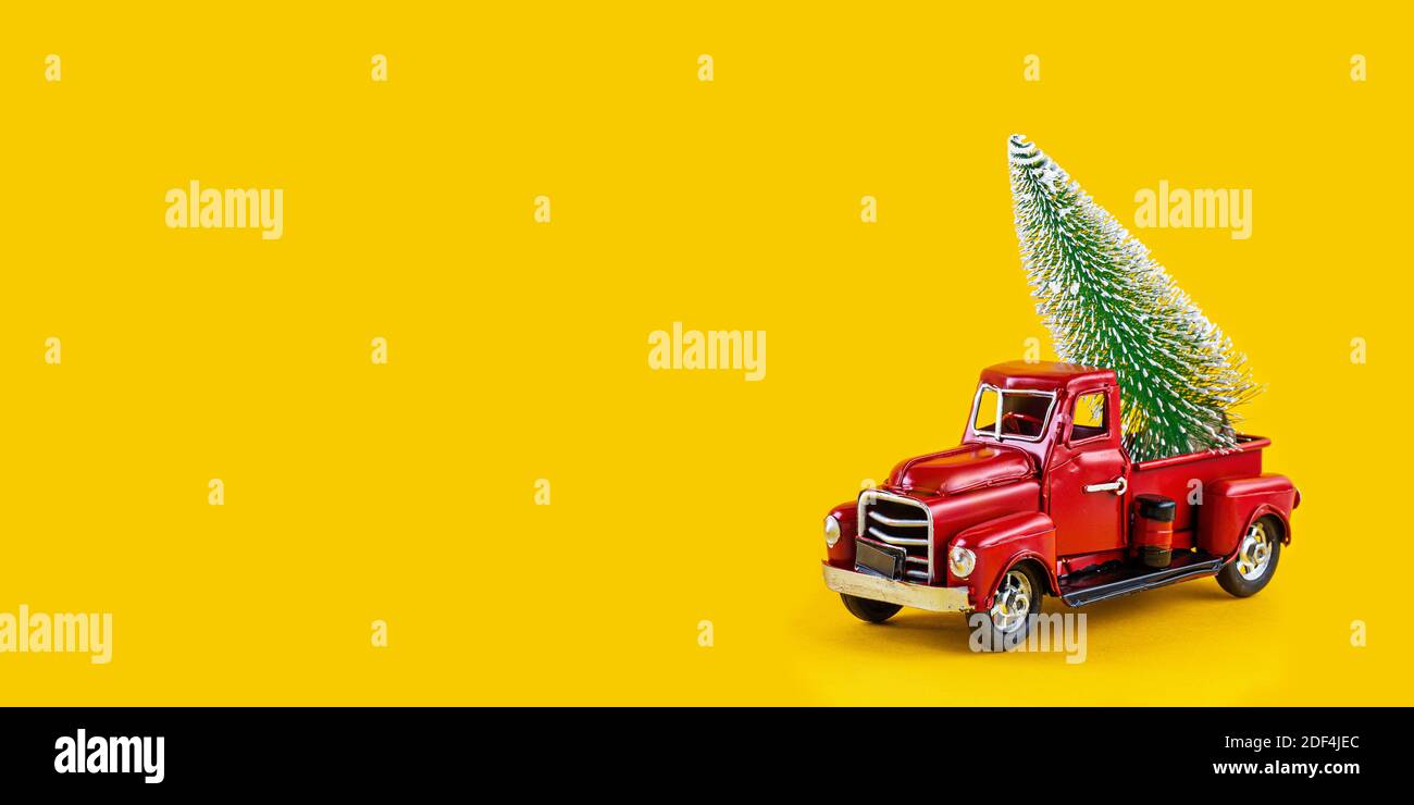 Camion giocattolo rosso retrò con albero di Natale sul corpo del camion su sfondo giallo. Consegna, natale, Capodanno. Modello giocattolo vintage con Christm Foto Stock