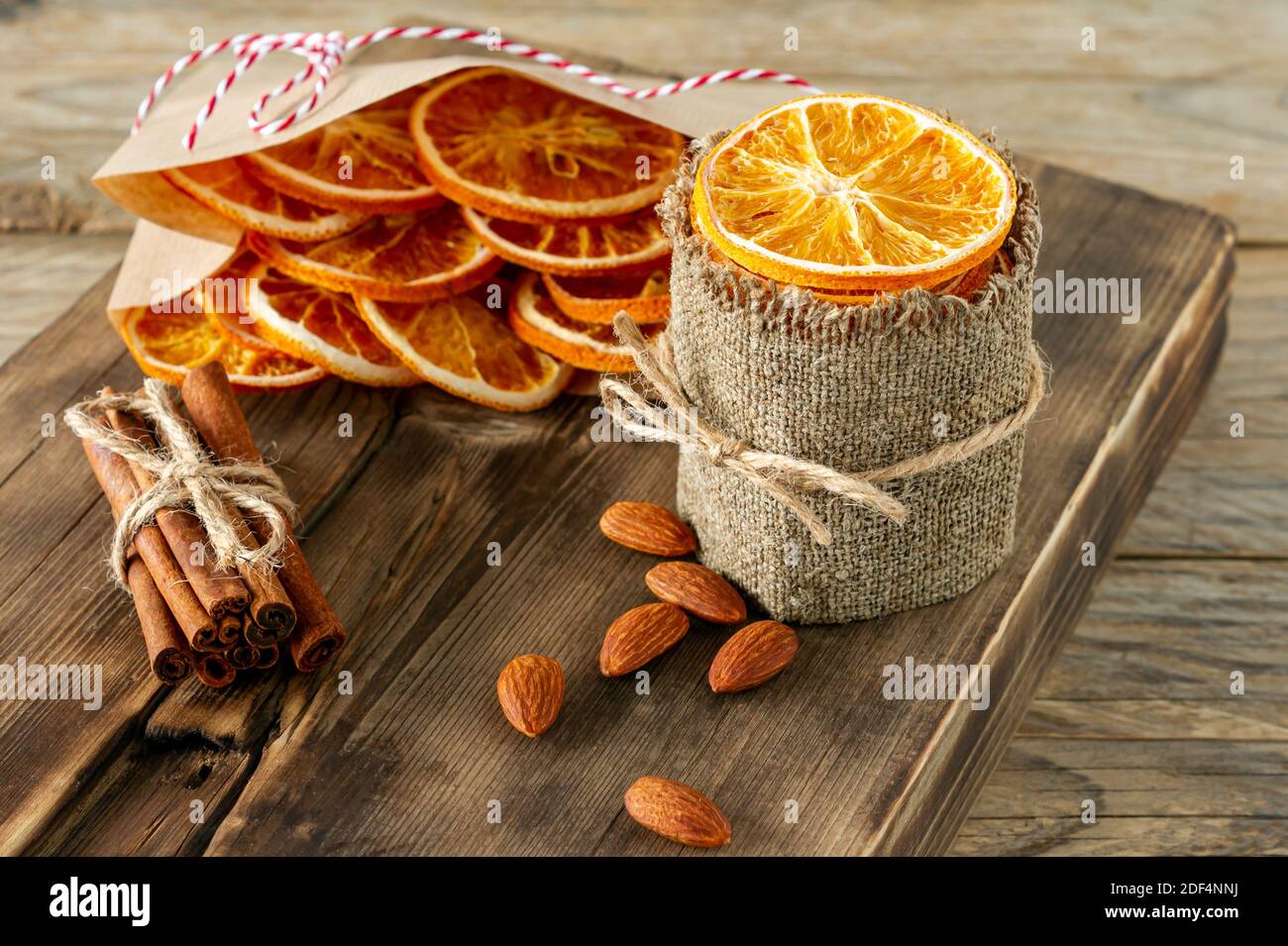 Composizione di Natale. Arrangiamento di arance secche, bastoncini di cannella e mandorla su sfondo di legno. Ingredienti rustici, spezie per le feste. Foto Stock