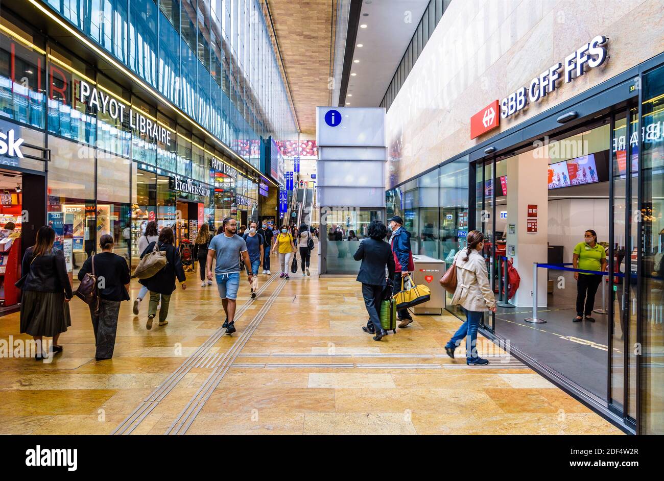 I passeggeri camminano lungo l'atrio trasversale della stazione ferroviaria di Ginevra, passando accanto ai negozi e al banco informazioni FFS CFF FFS. Foto Stock