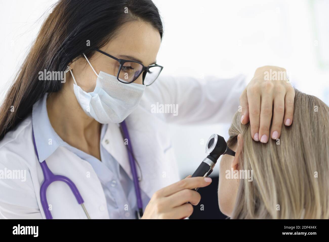 Otorhinolaringologo che guarda pazienti di sesso femminile all'orecchio con otoscopio in clinica Foto Stock