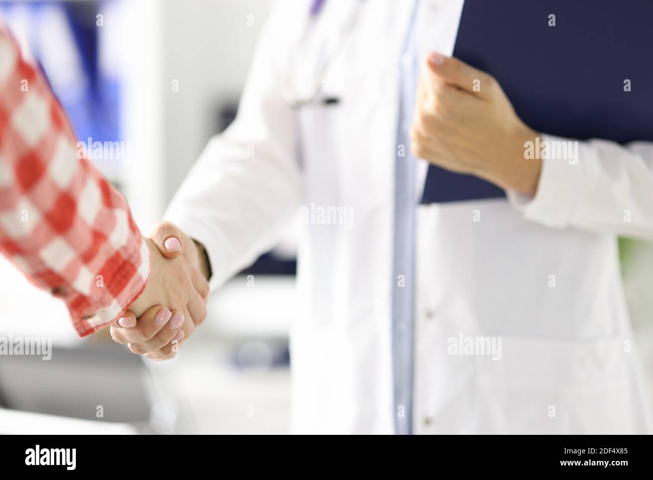 Medico che tiene gli appunti e agita la mano del paziente in clinica primo piano Foto Stock