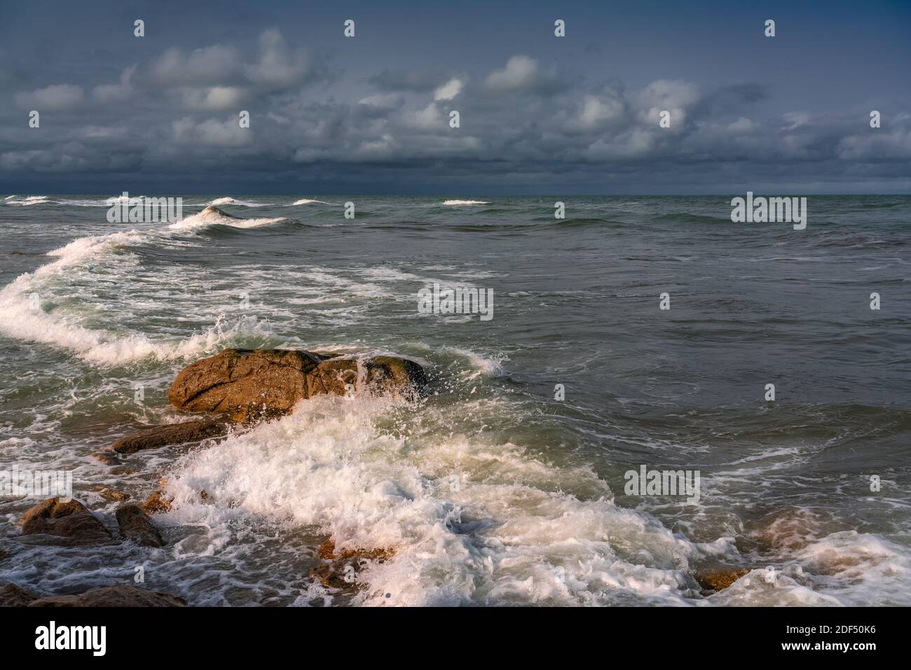 Spiaggia rocciosa vuota e mare tempestoso in tempo nuvoloso Foto Stock