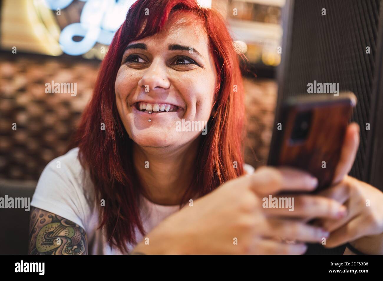Un ritratto closeup di una donna hipster positiva tatuata che si aggirava in un caffè Foto Stock