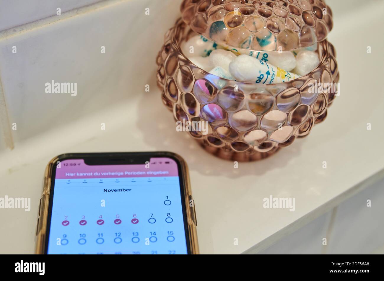 Berlino, Germania. 27 Nov 2020. Un calendario mestruale su uno smartphone si trova nel bagno accanto ad un contenitore con tamponi. Credit: Annette Riedl/dpa/Alamy Live News Foto Stock