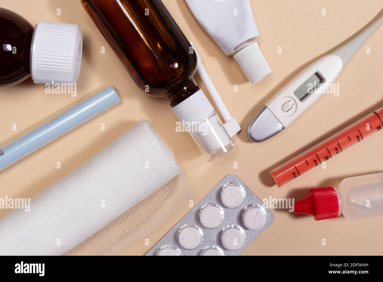 Bendaggio, flaconi di medicina, pillole e un termometro su uno sfondo beige chiaro. Foto per medicina e farmacia. Foto Stock