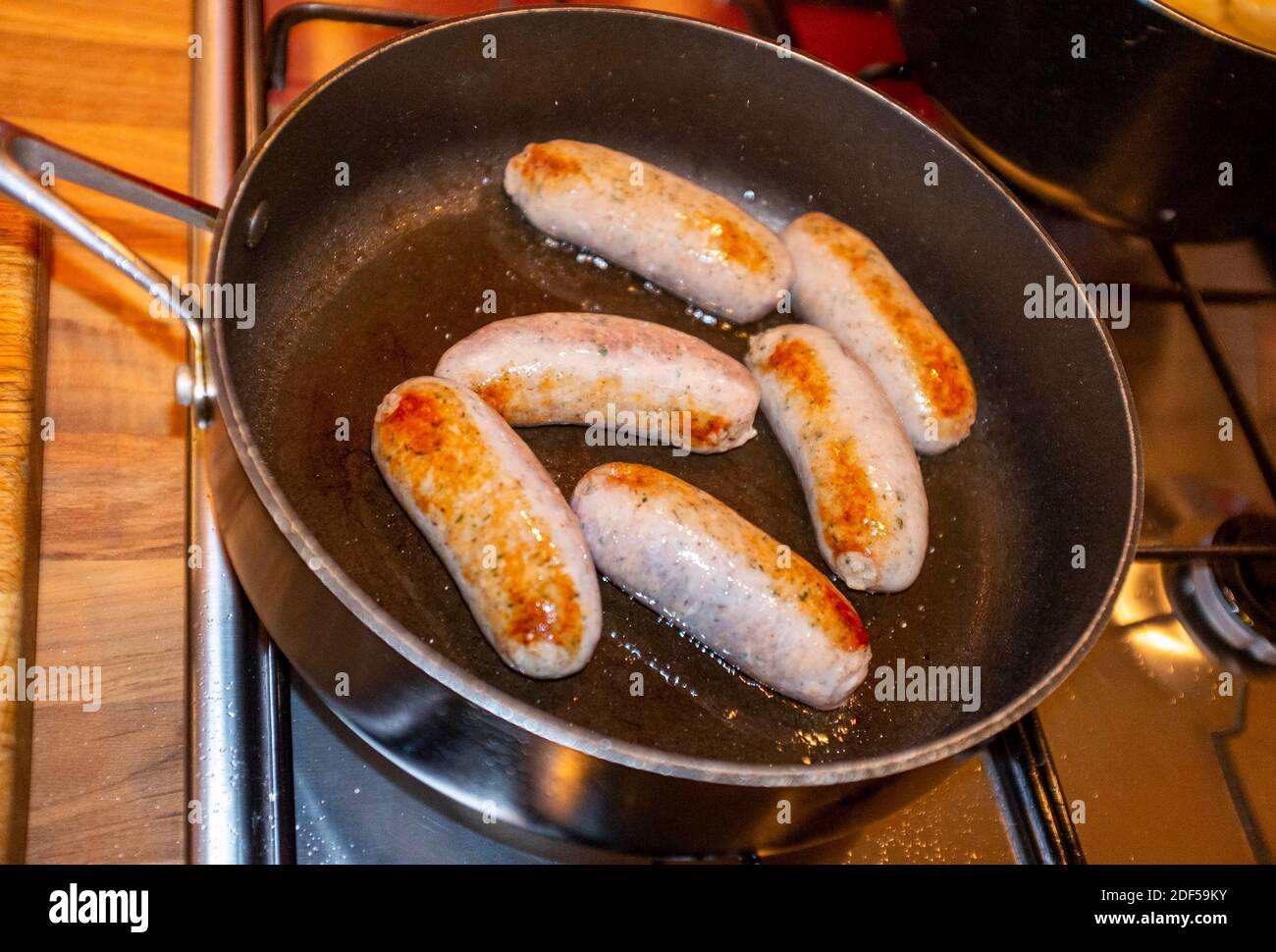 Dorare le salsicce di maiale fritte in una padella di salsa Foto Stock