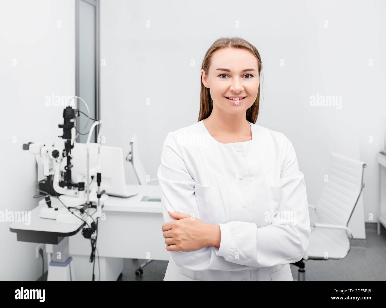 Ritratto di un'optometricia femminile positiva vicino ad apparecchiature oftalmiche in un moderno ufficio oftalmologico Foto Stock