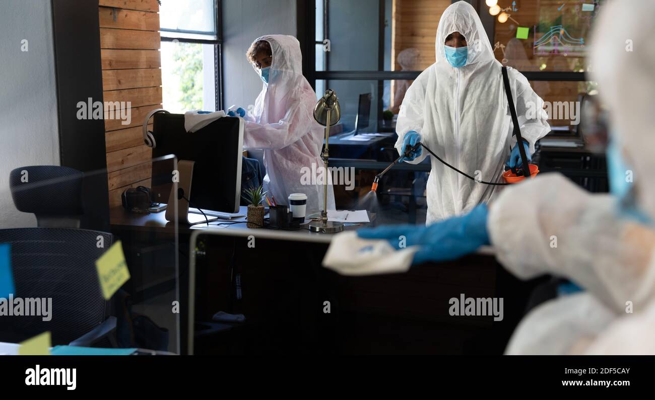 Detergenti misti che indossano abiti protettivi in ufficio Foto Stock