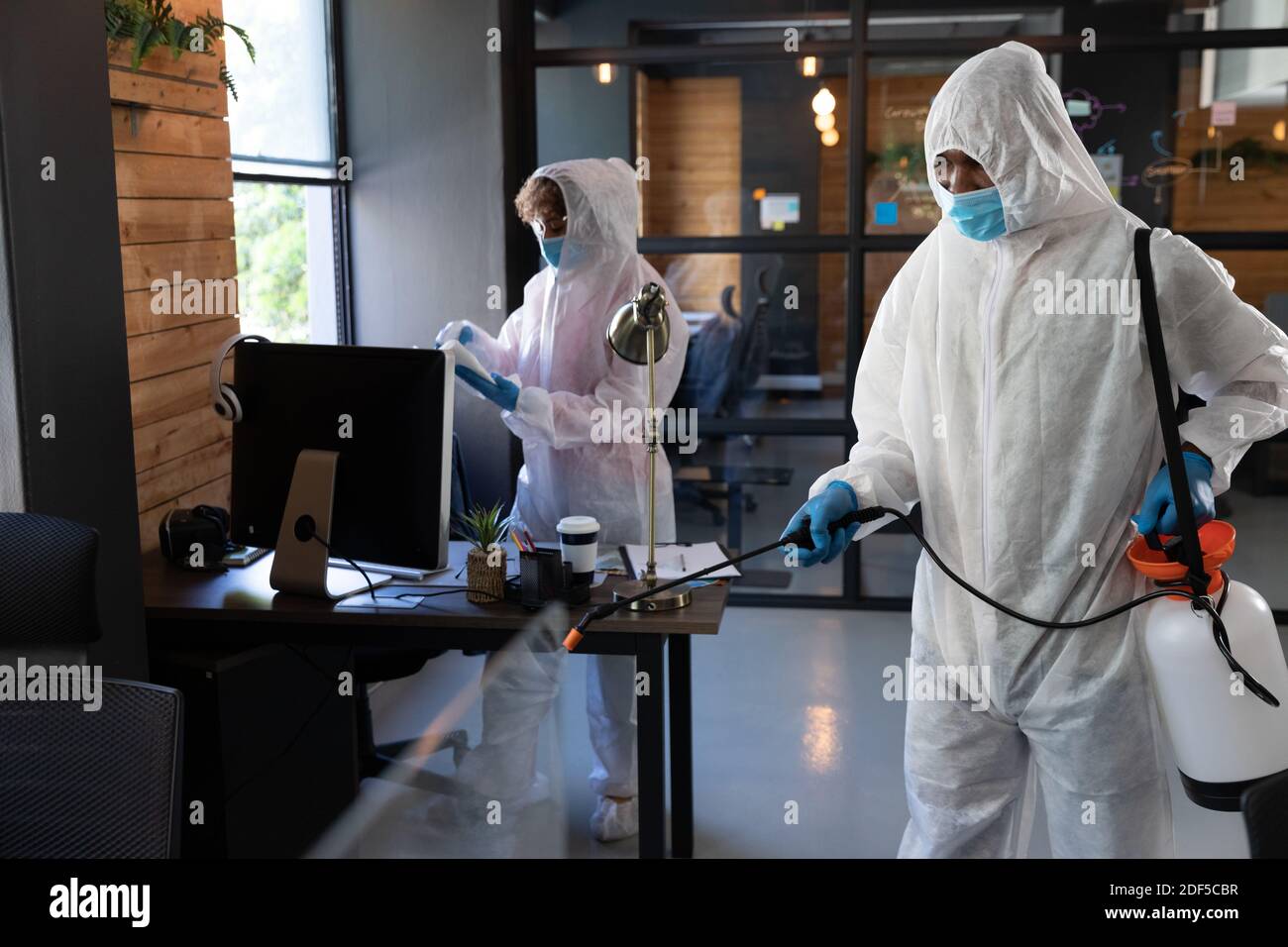 Detergenti misti che indossano abiti protettivi in ufficio Foto Stock
