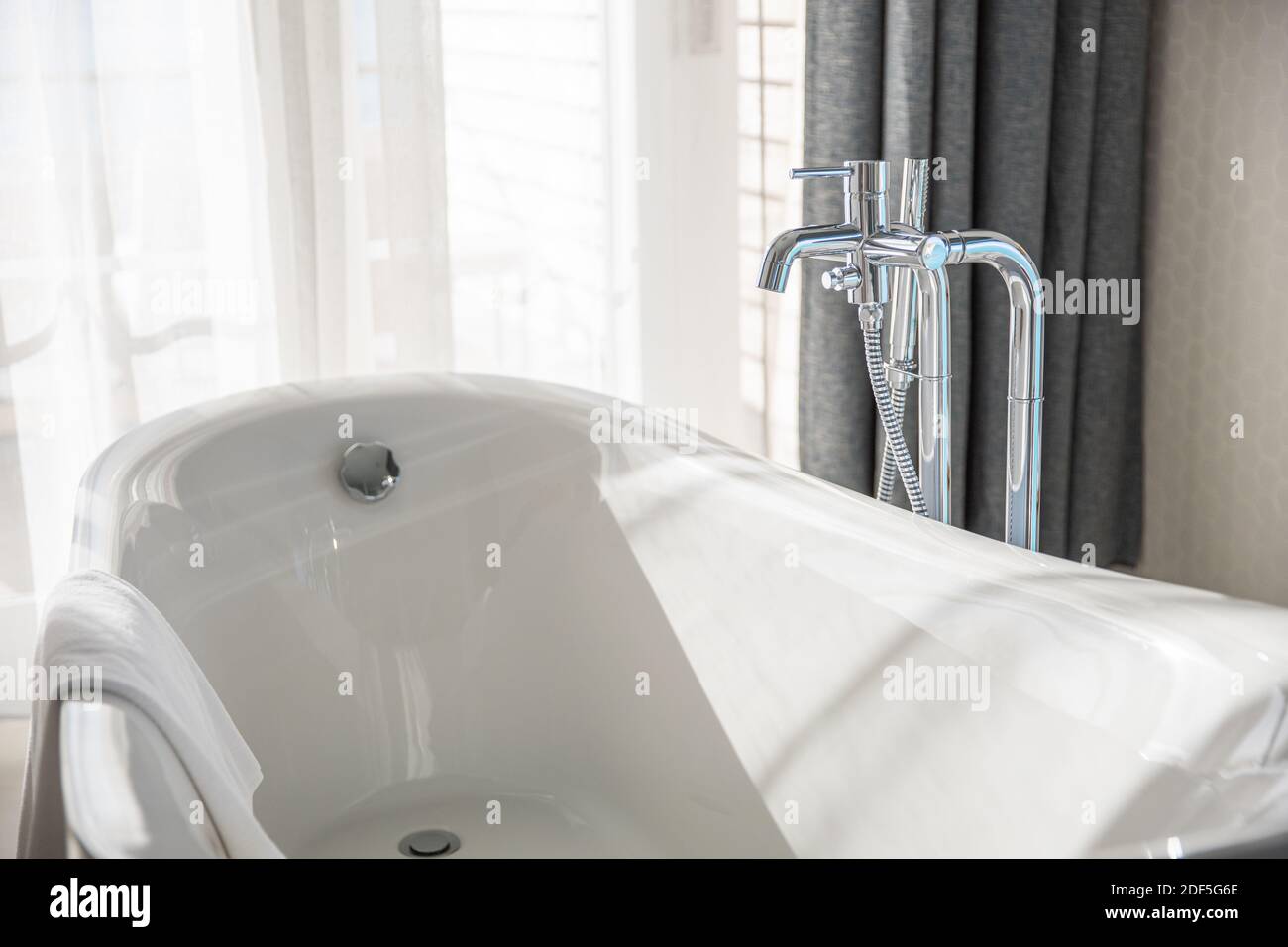 Moderna vasca bianca in un ampio bagno con parete di vetro. Elegante camera  spa del resort. Bagno bianco soleggiato con rubinetto cromato Foto stock -  Alamy