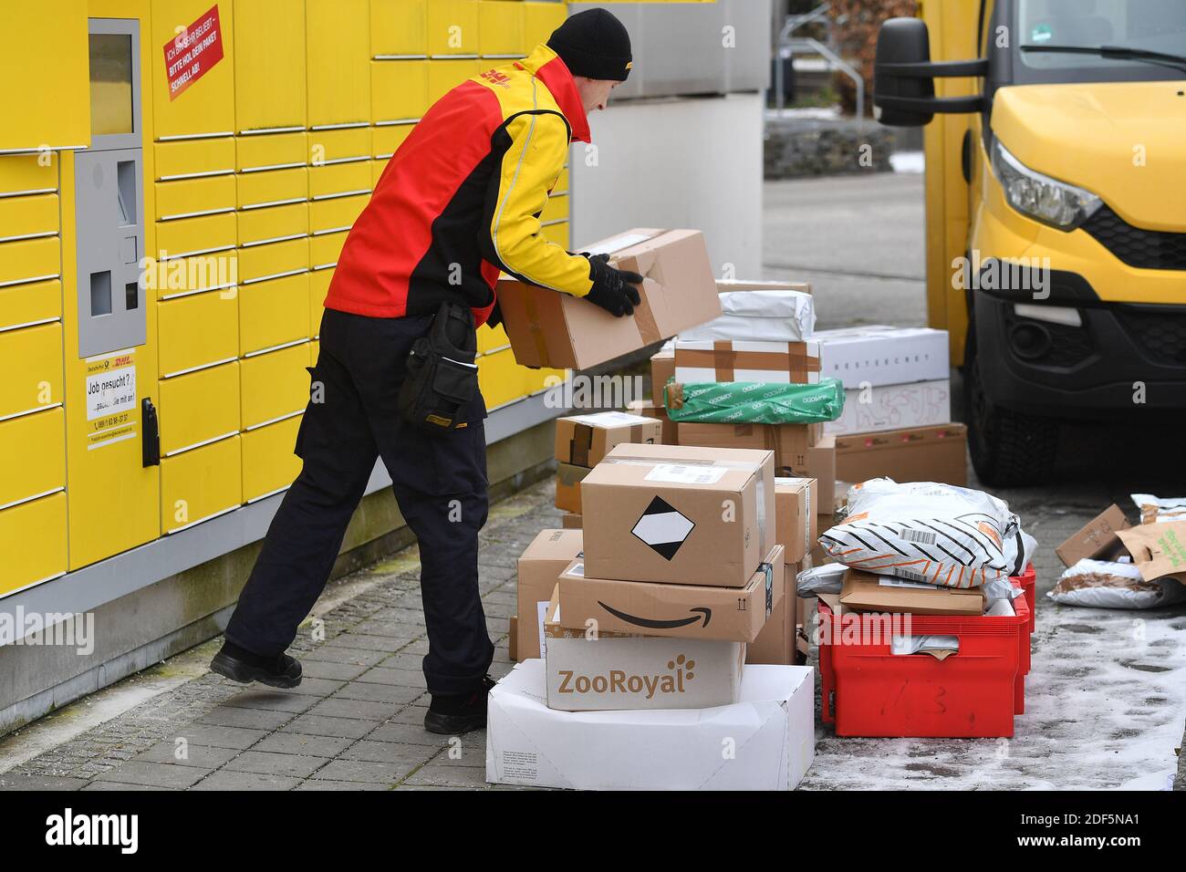 Monaco, Germania. 03 dic 2020. I volumi dei pacchi e il commercio online stanno fiorendo in tempi di pandemia del virus della corona. DHL spedizioniere, spedizioniere, al lavoro mette il pacco in un compartimento di una stazione di imballaggio. Scarica la sua vettura di pacco, il bus postale, DHL, pacco, pacchi, servizio di pacco, consegna, consegna, scarico, spedizione, trasportatore, camion a mano. | utilizzo in tutto il mondo credito: dpa/Alamy Live News Foto Stock