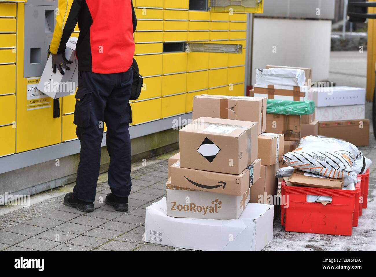 Monaco, Germania. 03 dic 2020. I volumi dei pacchi e il commercio online stanno fiorendo in tempi di pandemia del virus della corona. DHL spedizioniere, spedizioniere, al lavoro mette il pacco in un compartimento di una stazione di imballaggio. Scarica la sua vettura di pacco, il bus postale, DHL, pacco, pacchi, servizio di pacco, consegna, consegna, scarico, spedizione, trasportatore, camion a mano. | utilizzo in tutto il mondo credito: dpa/Alamy Live News Foto Stock