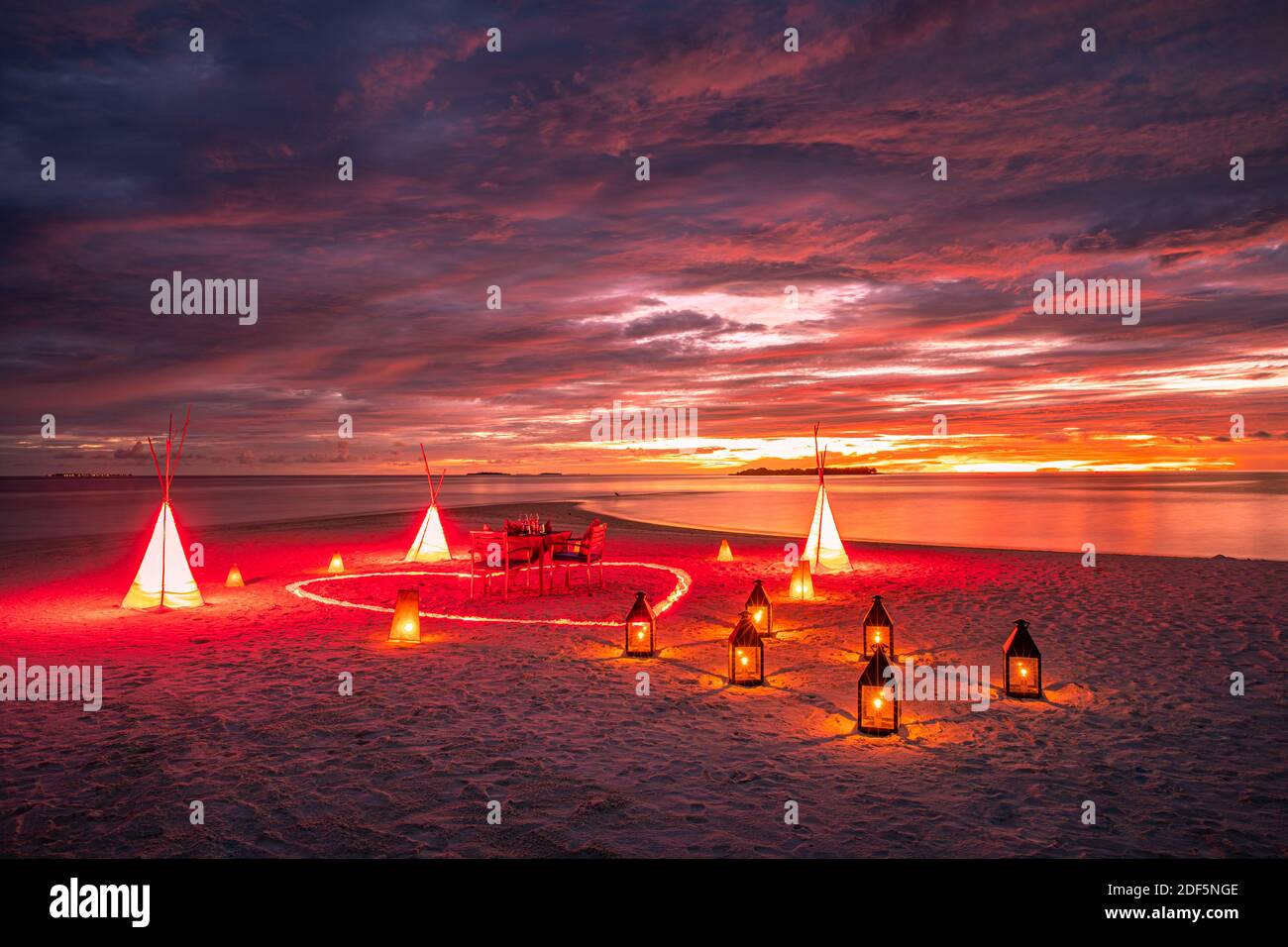 Una destinazione fantastica con candele e forma a cuore con luci a LED sotto il meraviglioso cielo del tramonto. Romantica coppia amore luna di miele concetto vicino al mare Foto Stock