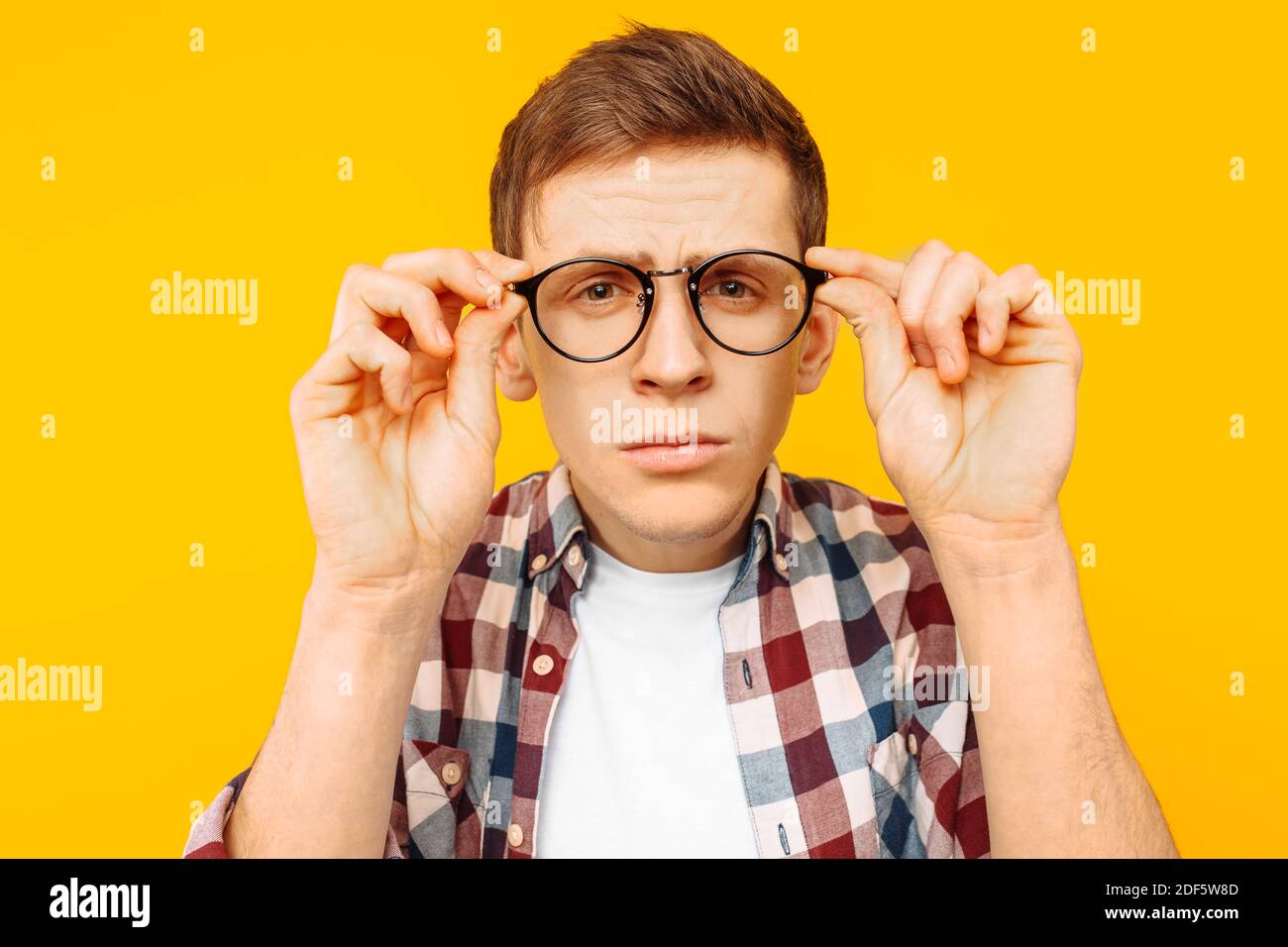 uomo con occhiali che si eyeing su uno sfondo giallo, un ragazzo con scarsa vista Foto Stock