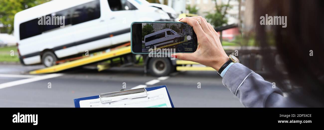 Donna agente di assicurazione film rotto minibus su smartphone Foto Stock
