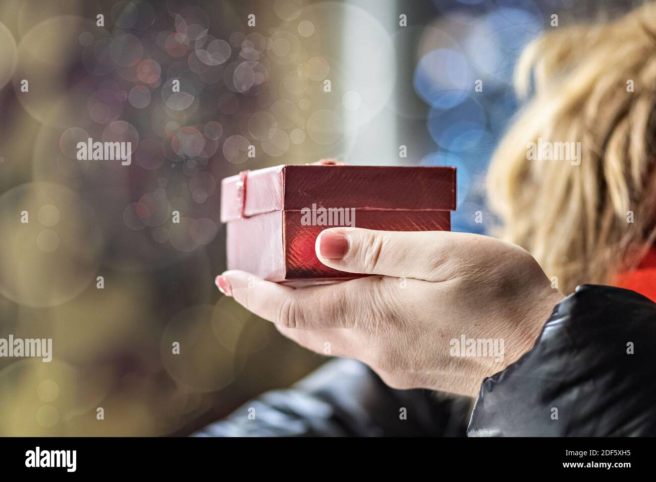 Una donna apre una scatola rossa festiva con un regalo. Vacanze di Natale. Foto Stock