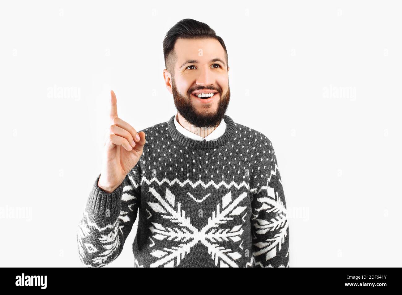 Un'immagine di un uomo sorridente che ha un'idea. Un bel ragazzo bearded in un maglione appena venuto in su con un pensiero grande. Su sfondo bianco Foto Stock