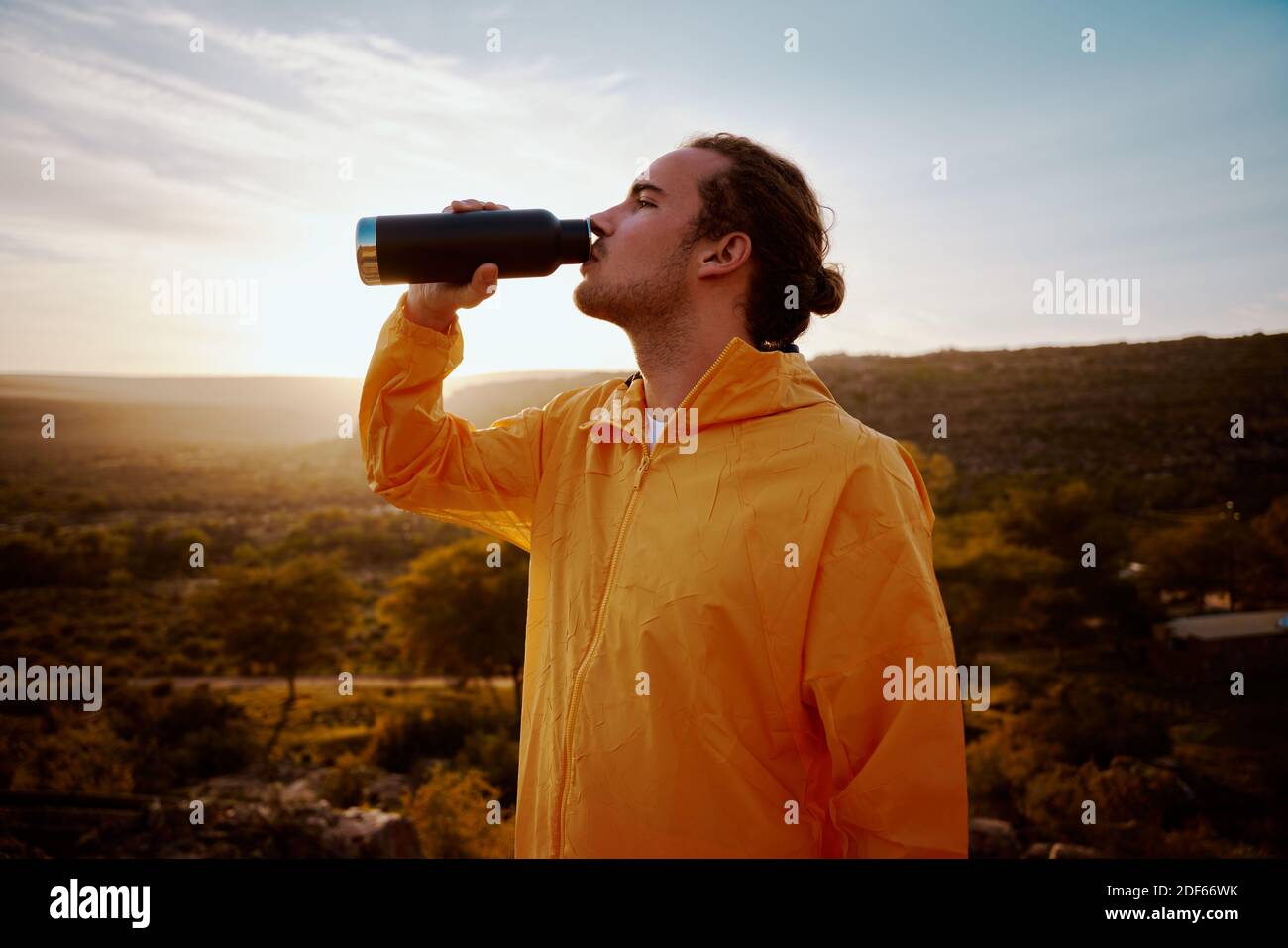 Ritratto di giovane uomo che beve acqua dalla bottiglia mentre si riposa dopo l'esecuzione Foto Stock