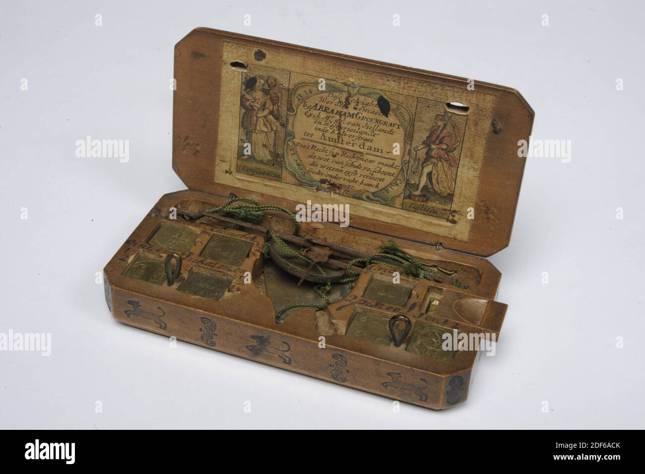 Jan Kaan, 1639, rame, corda, legno, ferro, carta, Generale: 4 x 15.3 x 8.8cm 40 x 153 x 88mm, scatola peso con due cassetti, bilancia e 31 pesi. Il coperchio è dotato di due ganci di bloccaggio lavorati, l'intera scatola ha ampie sculture in legno con motivi floreali. All'interno del coperchio un'incisione con le immagini e i nomi delle monete e i relativi pesi. Pesi multipli non corrispondono alle immagini. Nella cartouche centrale una rappresentazione di un uomo dietro un leggio, una donna al tavolo e la morte con clessidra, sopra la quale lo stemma di Amsterdam. Nella foto il testo: Luc. 12 circa Le Bien Foto Stock