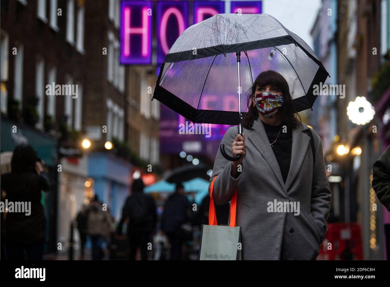 Uno shopper indossa una maschera a Carnaby Street, Londra, dopo la fine del secondo blocco nazionale e l'Inghilterra ha un sistema rafforzato di restrizioni del coronavirus. Foto Stock