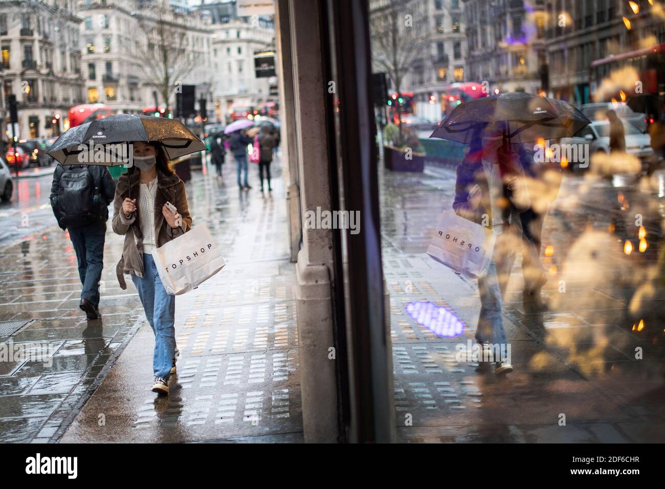 Un acquirente indossa una maschera facciale in Regent Street, Londra, dopo la fine del secondo blocco nazionale e l'Inghilterra ha un sistema rafforzato di restrizioni al coronavirus. Foto Stock