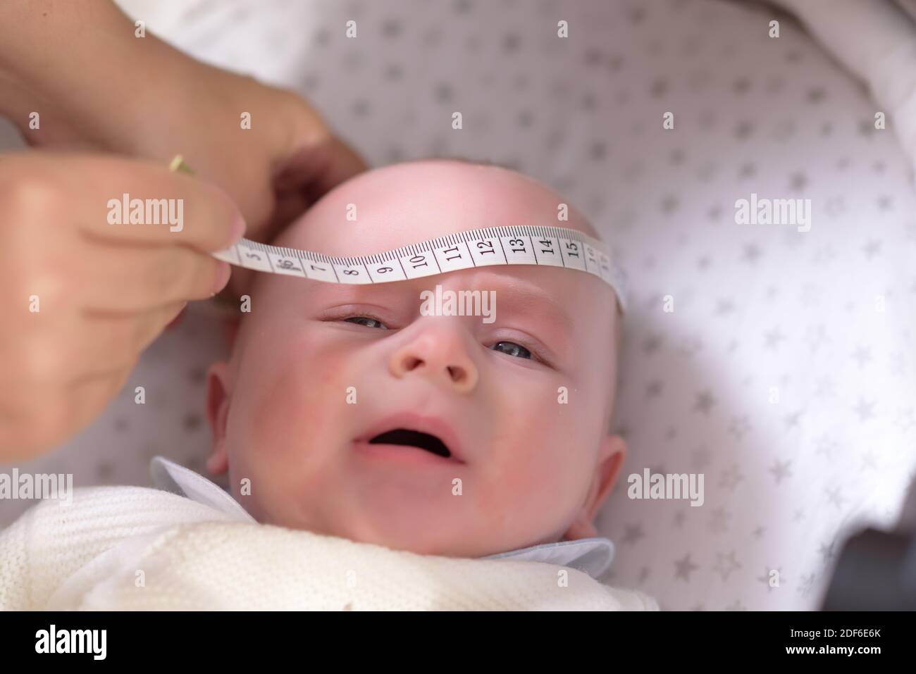 Misurare il nastro in mano misurando la testa del bambino isolata Foto Stock