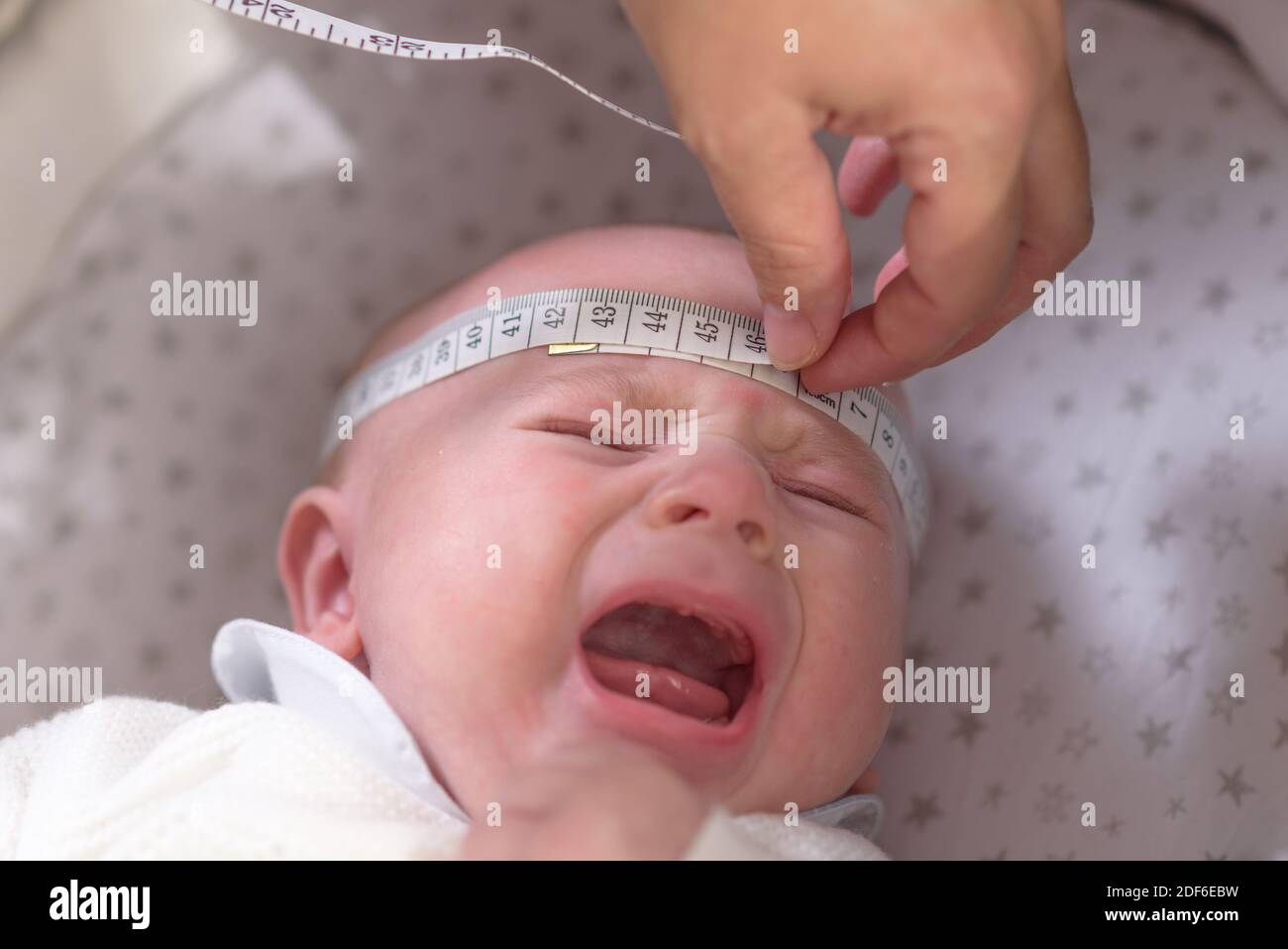 Misurare il nastro in mano misurando la testa del bambino isolata Foto Stock