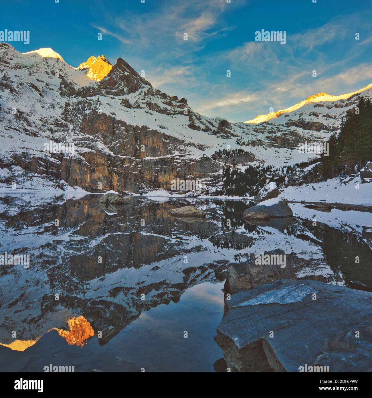 Paesaggio panoramico della Svizzera con neve, montagna e lago in inverno. Luoghi da visitare a Kandersteg. Riflessione di montagna e cielo sulle acque del lago. Foto Stock