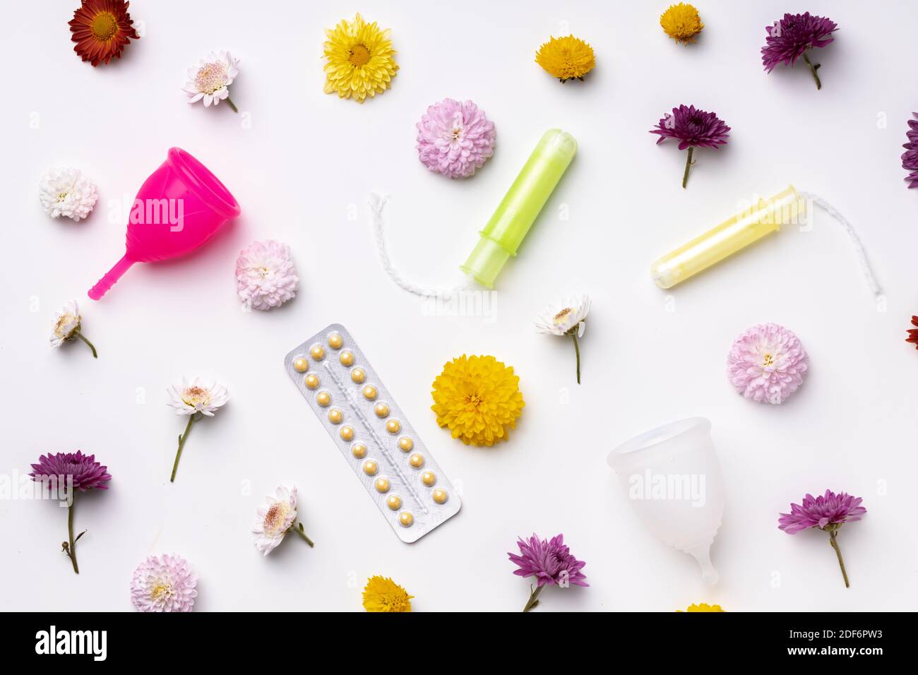 Coppa mestruale, contraccettivi orali e tamponi medici con vista dall'alto dei fiori Foto Stock