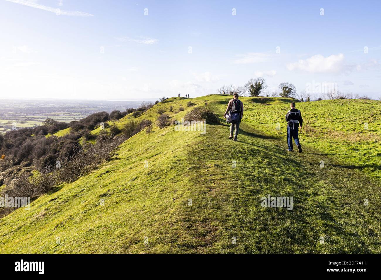 Gli escursionisti camminano lungo il bastione di una leggera collina in uniforme dell'Età del ferro su Ring Hill presso il punto di vista di Cotswold di Haresfield Beacon, Gloucestershire Foto Stock