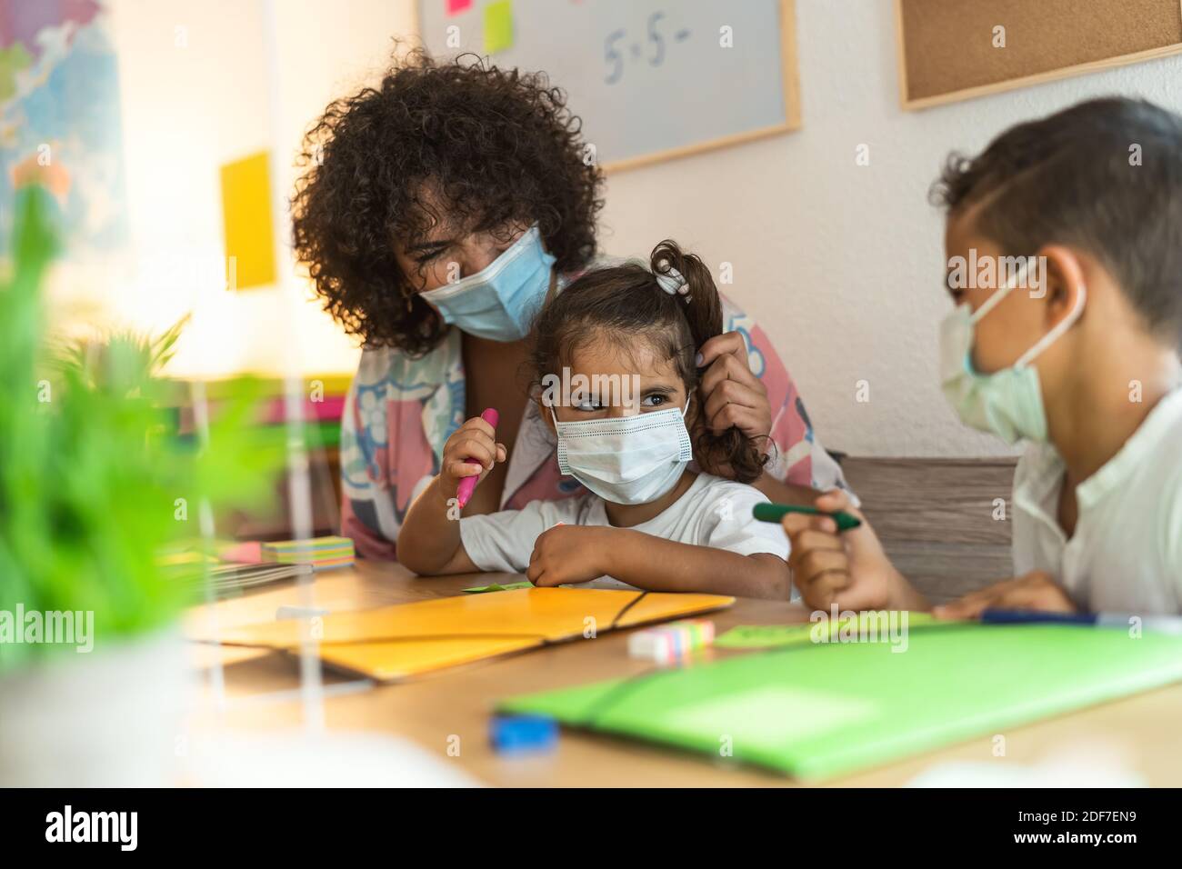 Insegnante con bambini che indossano maschera in classe prescolare durante pandemia del virus della corona - concetto di sanità e istruzione Foto Stock