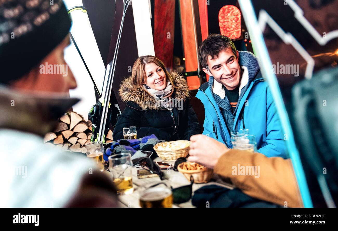 Amici felici che bevono birra e mangiano patatine all'aperto apareski - giovani che si divertono insieme al ristorante del bar notturno dopo aver sciato Foto Stock