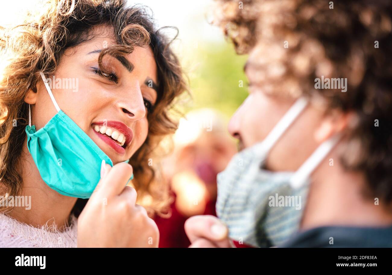 Coppia felice di amanti che si guardano l'un l'altro con aperto Maschera facciale - concetto di amore e speranza a tempo di covid con l'uomo e la donna in relazione tenera Foto Stock