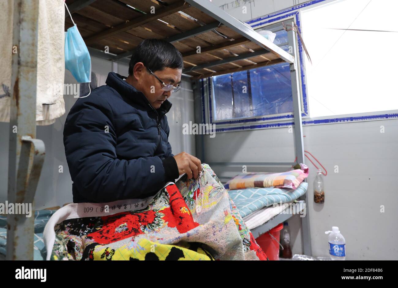 Shanghai. 2 dicembre 2020. Zhang Xingfa lavora su un pezzo di punto a croce nel suo capanno temporaneo nel comune di Shanghai della Cina orientale, 2 dicembre 2020. Zhang Xingfa, 54 anni, è un esperto saldatore che attualmente lavora in un cantiere nella zona speciale di Lingang a Shanghai. Ha avuto accidentalmente un'esperienza di prima mano con l'arte del punto a croce anni fa, e non potrebbe mai rompersi da allora. Zhang prende grande piacere nel punto croce, e vede la somiglianza tra il suo hobby e la sua professione - entrambi comandano molta pazienza e precisione. Credit: Fang Zhe/Xinhua/Alamy Live News Foto Stock