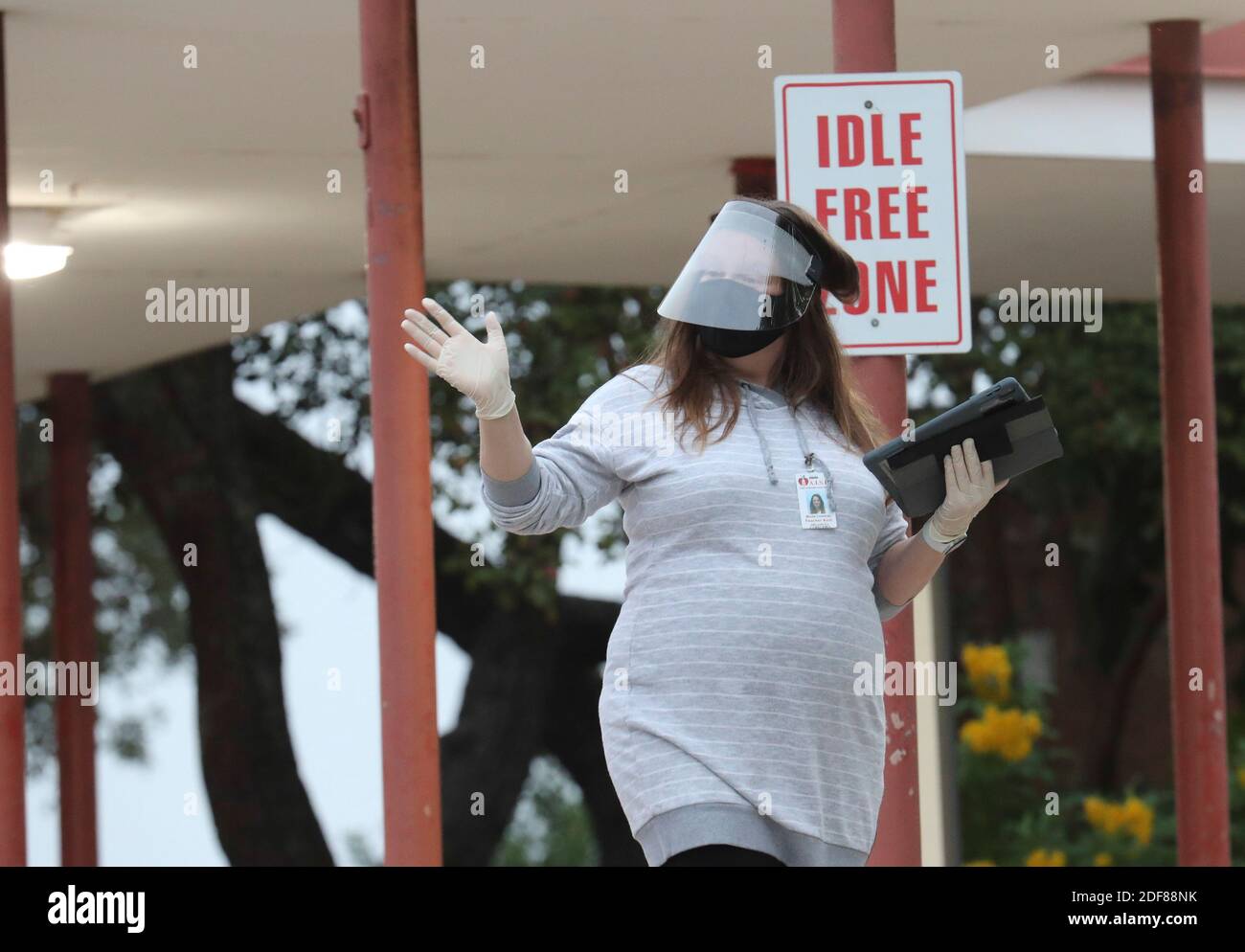 Assistente di insegnamento Nicole Cormican ondeggia ai nuovi studenti mentre si effettuano i check-in per i bambini per il secondo giorno di lezioni di persona a Barton Hills Elementary nel sud di Austin. Tutte le temperature degli studenti sono state controllate e per entrare nell'edificio sono state richieste coperture facciali. ©Bob Daemmrich Foto Stock