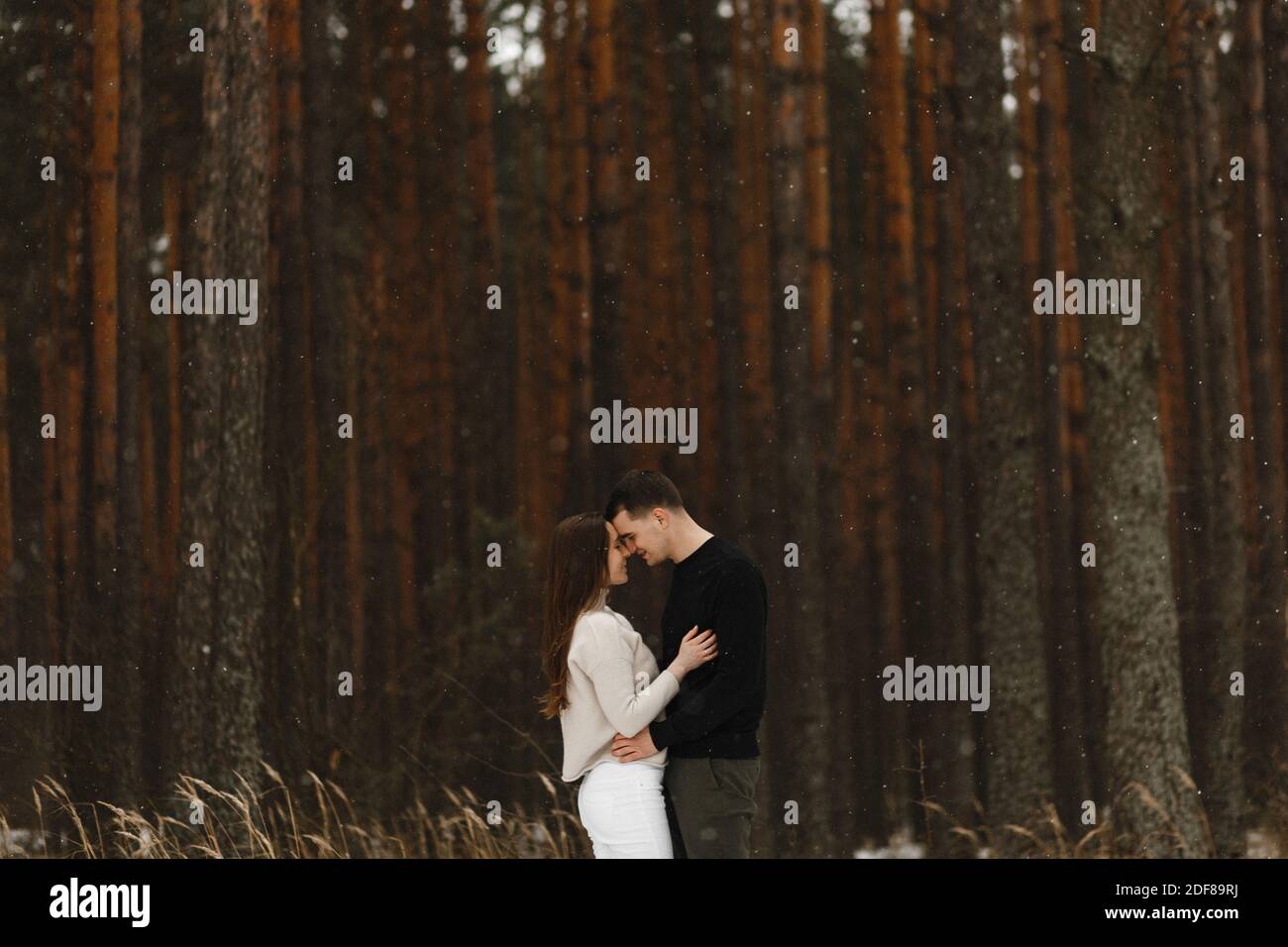 Coppia sorridente innamorata abbracciando nella foresta invernale. Inserire il testo. Amore, rapporto, vacanze invernali. Idee di foto di coppia di inverno Foto Stock