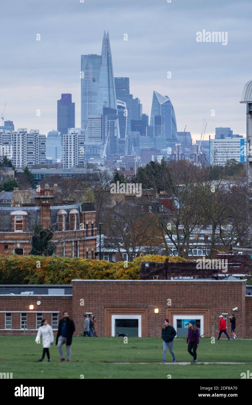 Persone che camminano nel Brockwell Park con il Lido di Brockwell e il paesaggio urbano di Londra sullo sfondo, Londra Foto Stock
