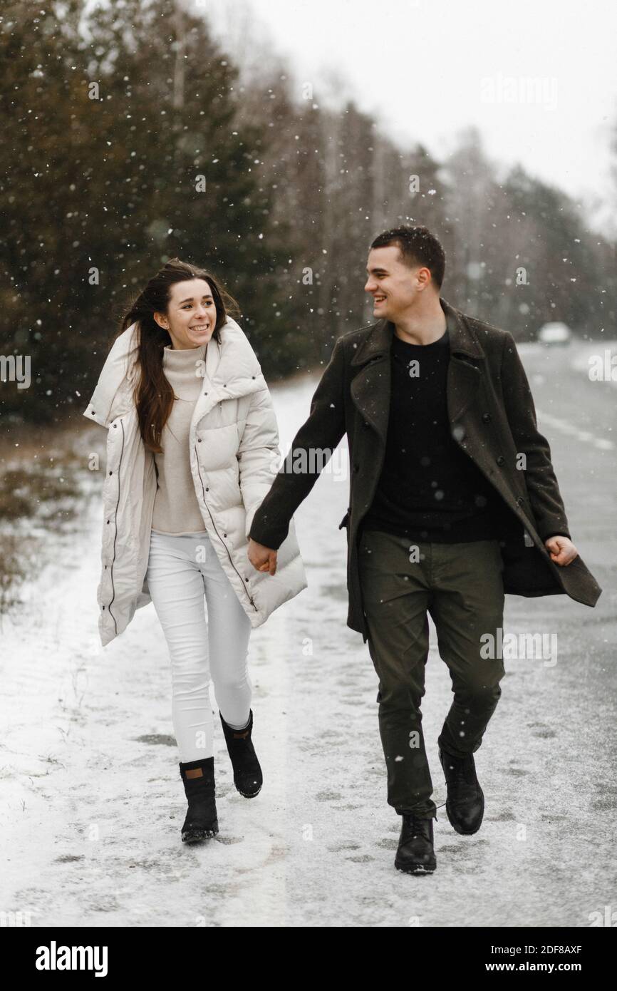 Felice coppia innamorata camminando sulla neve sullo sfondo della foresta invernale. Amore, rapporto, vacanze invernali. Idee di foto di coppia di inverno Foto Stock
