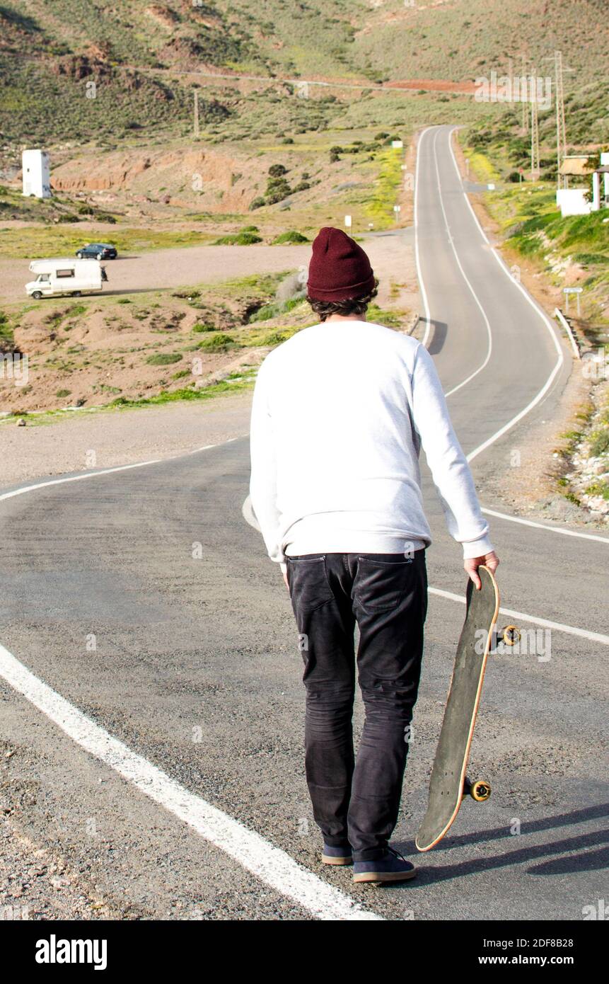 uomo skateboard lungo una lunga strada tortuosa attraverso il deserto Foto  stock - Alamy