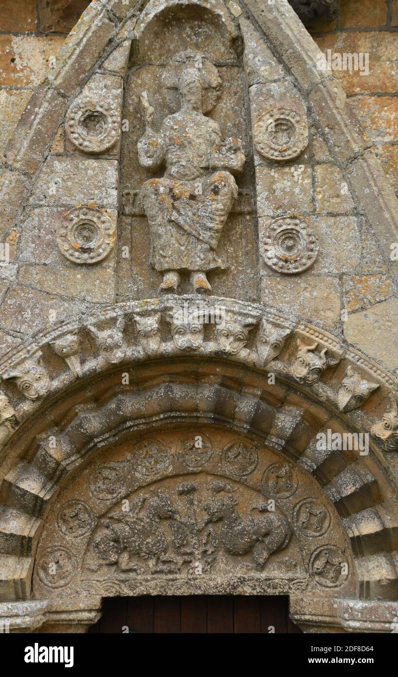 Timpano normanno sopra la porta Nord nella Chiesa di tutti i santi, Lullington, Somerset.The albero della vita che viene mangiato da un paio di mostri sopra t Foto Stock