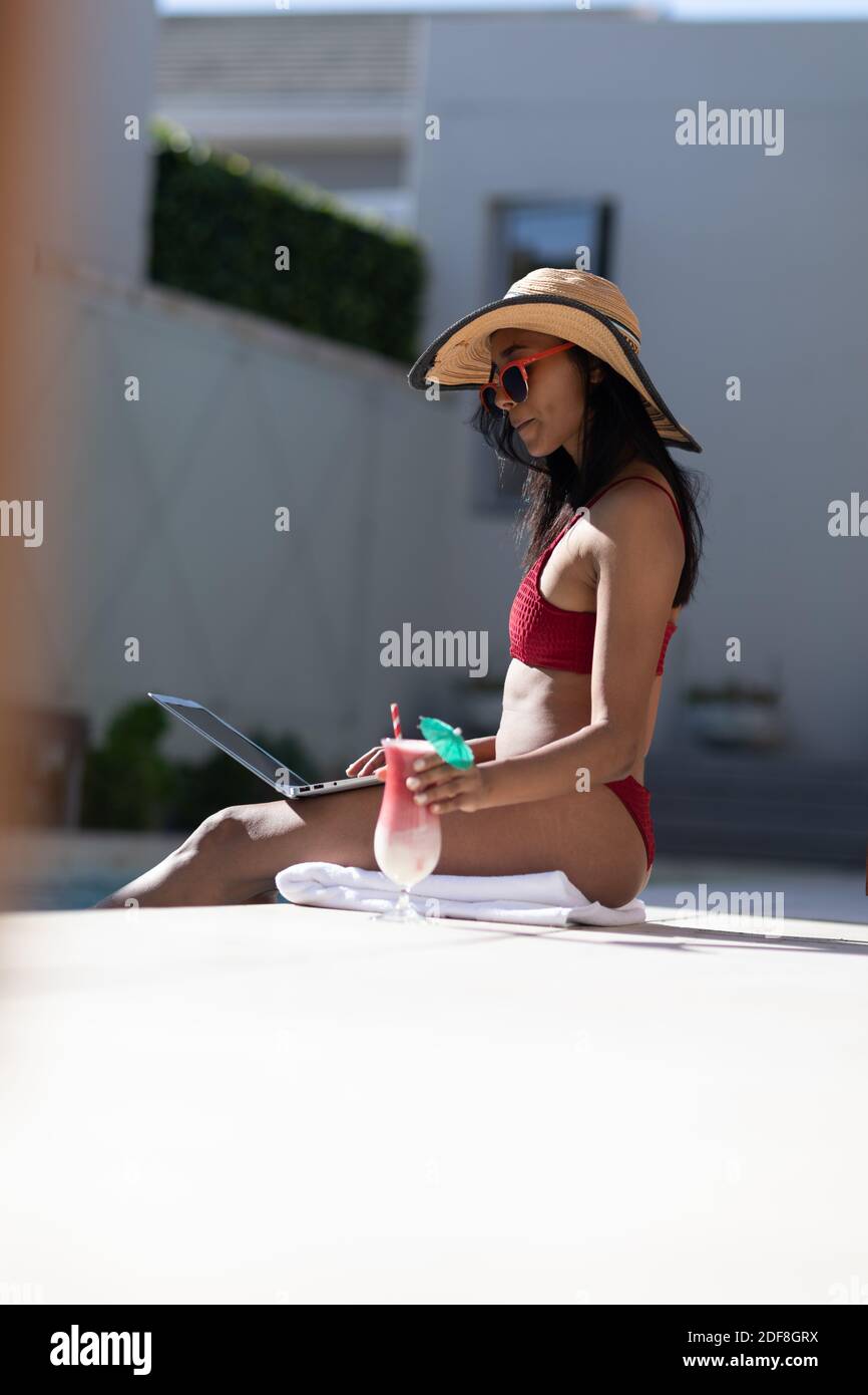 Donna di razza mista seduta in piscina a casa Foto Stock