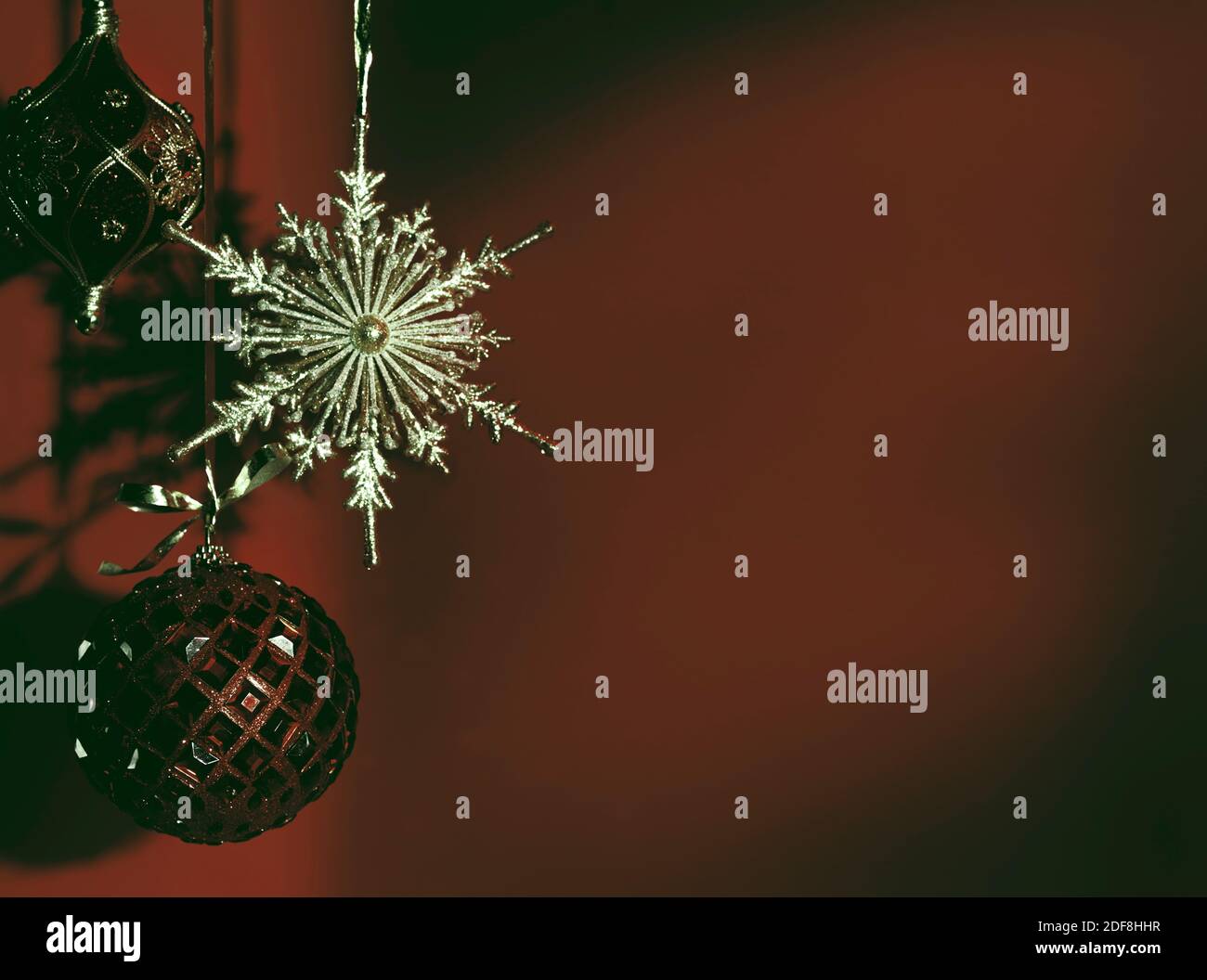 Brillante ornamento di Natale su sfondo rosso scuro sbiadito. Vacanze invernali artistiche, concetto di nuovo anno con spazio di copia. Foto Stock