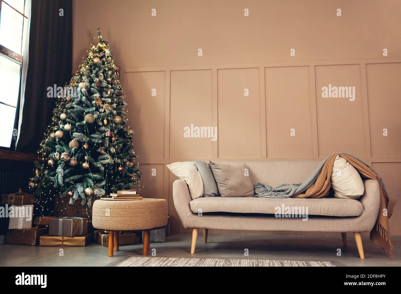Interni dello studio di Natale con albero di Natale decorato, scatole regalo e divano accogliente. Studio fotografico vuoto di Capodanno e Natale Foto Stock