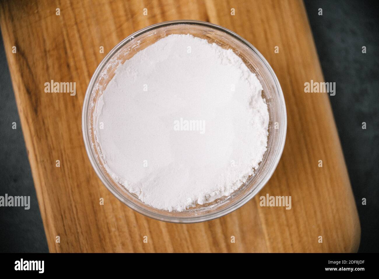 contenitore in vetro di farina su tagliere di legno Foto Stock